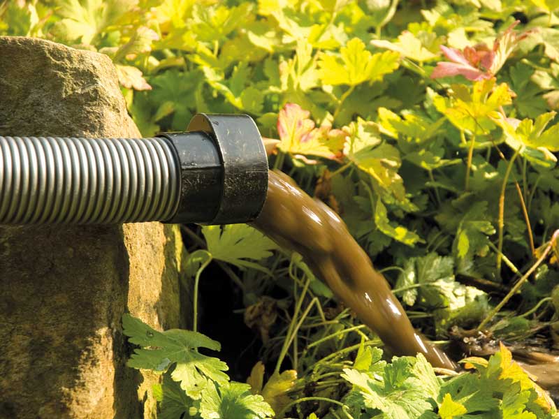 Schmutzwasser laeuft aus dem Sauger in den Garten
