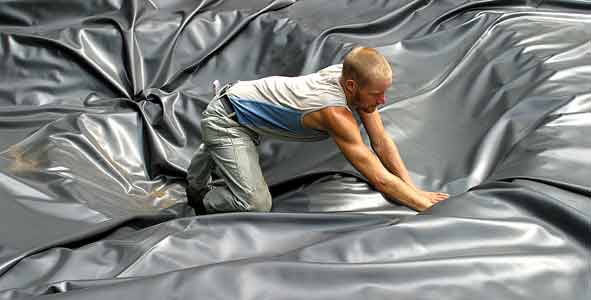 Ein Mann streich die Teichfolie glatt